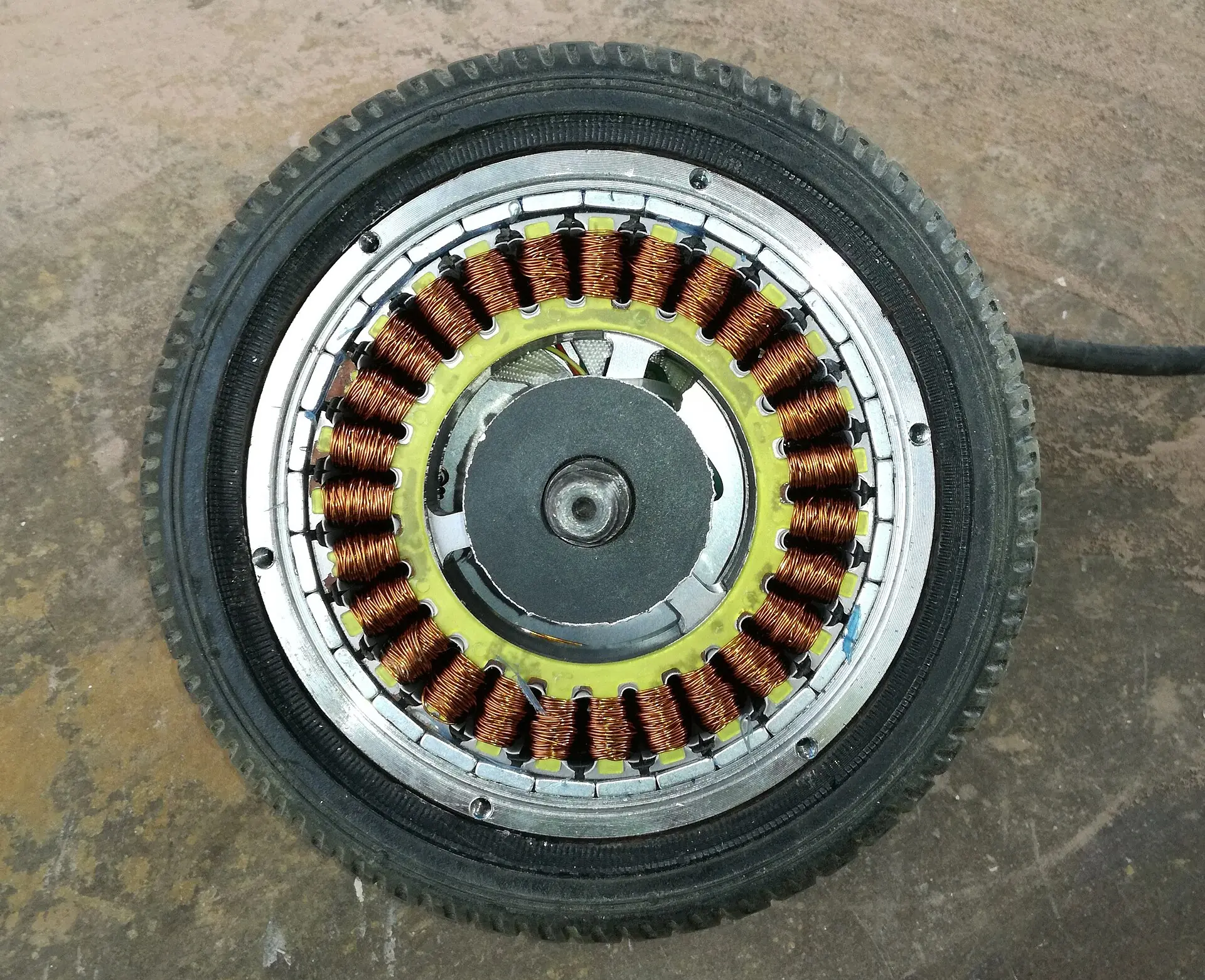 A brushless hub motor with its side panel removed, showing copper stator windings inside the wheel